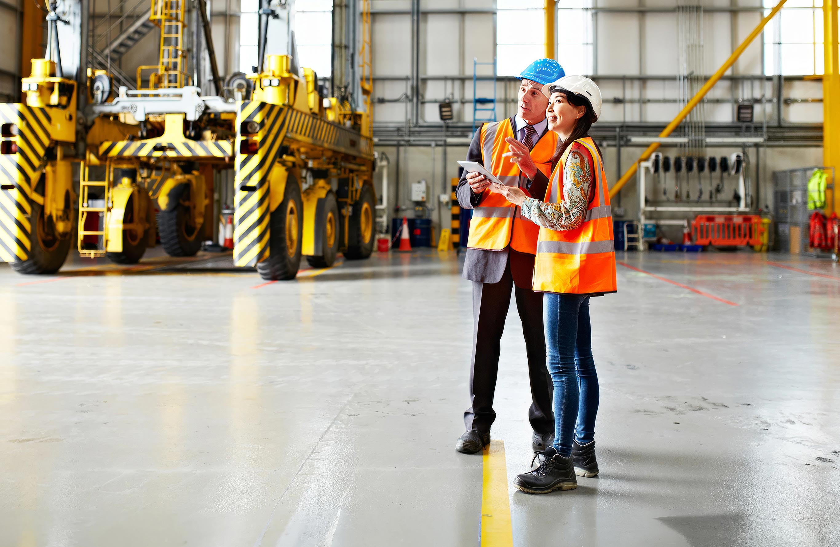 Header Image. Factory floor with two managers in high vis vests